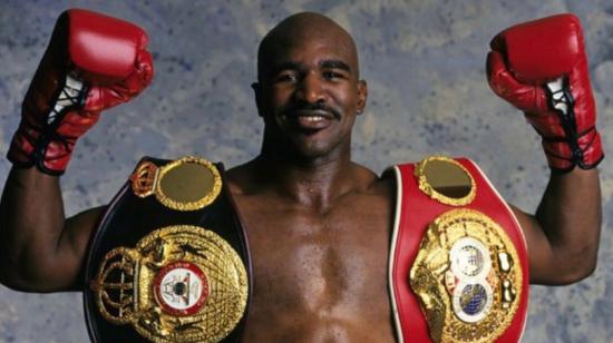 Evander Holyfield con sus cinturones de campeón en boxeo.