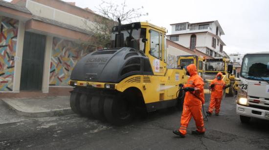 Dos obreros del Municipio de Quito desinfectan las maquinaria antes del reinicio de la repavimentación, el lunes 18 de mayo de 2020.