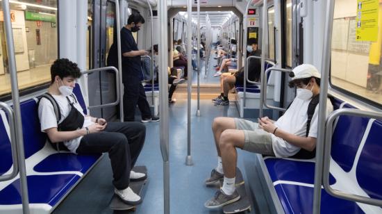 Unos jóvenes viajan con sus máscaras y guardando las distancias de seguridad en el Metro de Barcelona, para protegerse del coronavirus, este lunes 25 de mayo cuando la ciudad entra en la fase 1 de la desescalada.