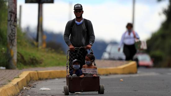 Un ciudadano venezolano y dos niños caminan por la carretera, de regreso a Venezuela, el jueves 21 de mayo en Quito, Ecuador.