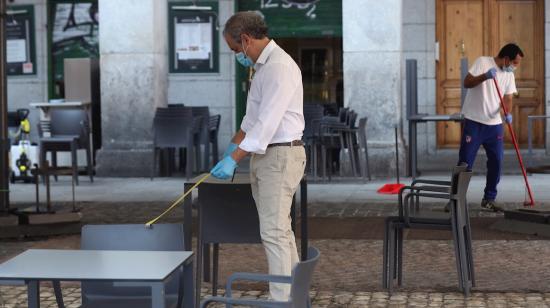 Un camarero comprueba la distancia entre mesas en la terraza de su bar de la Plaza Mayor en Madrid, 25 de mayo de 2020.