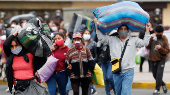 Ambulantes se desplazan luego de ser desalojados por la Policía de una vía pública donde vendían sus productos, el viernes 12 de junio en Lima.