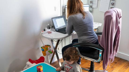 Imagen ilustrativa. Mujer junto a su hijo en una sesión de teletrabajo.