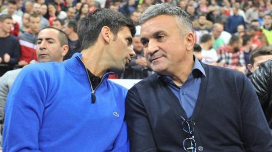 Novak Djokovic junto a su padre, Srdjan Djokovic conversando durante un partido de tenis.