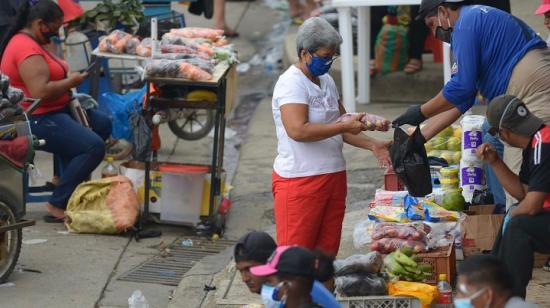 Una mujer compra a un vendedor ambulante en la Casuarina, en la Av. Perimetral, de Guayaquil, el 24 de mayo. 