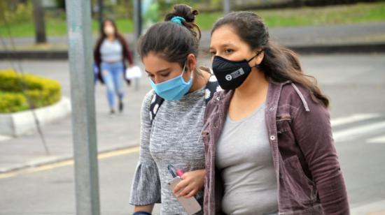 Ciudadanas en Quito caminan portando mascarillas, medida de prevención contra el coronavirus. 