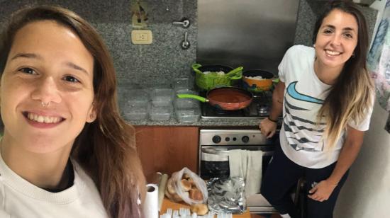 Daiana Leguizamón (d) con su pareja Carolina Teisseire (i), mientras cocinan para personas sin hogar en Buenos Aires.