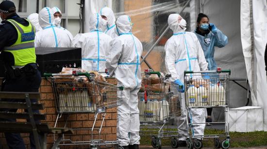 Bomberos vistiendo trajes de bioseguridad reparten comida en un barrio de Melbourne, Australia, el 7 de julio. 