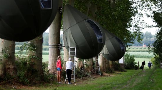 Dos personas suben una escalera para llegar a la carpa en forma de lágrima que cuelga de un árbol creada por el artista holandés Dre Wapenaar, que ofrece un alojamiento inusual para turistas en el campo, cerca de Borgloon, Bélgica, el 7 de julio de 2020.