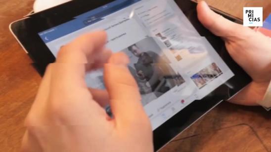 Una persona sostiene una tableta y revisa la red social Facebook.
