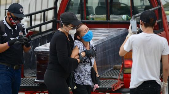 Una mujer llora junto al ataúd de su familiar en la entrada de un cementerio de Guayaquil, el 15 de abril. 