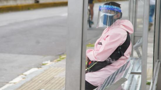 Una ciudadana con todas las medidas de bioseguridad espera en una parada de bus en Quito, 27 de julio de 2020.