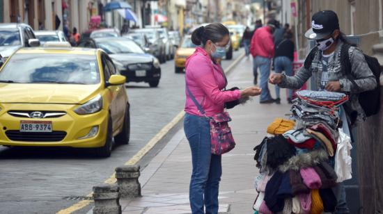 Una mujer compra un gorro de lana a un comerciante en el Centro Histórico de Cuenca, el 17 de julio de 2020.