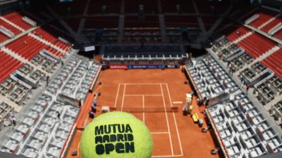 Imagen de la cancha del Mutua Madrid Open sin público y una pelota de tenis haciendo referencia al torneo.