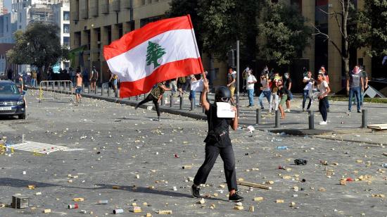 Una manifestante sostiene una bandera de Líbano afuera del Parlamento, el 8 de agosto de 2020.