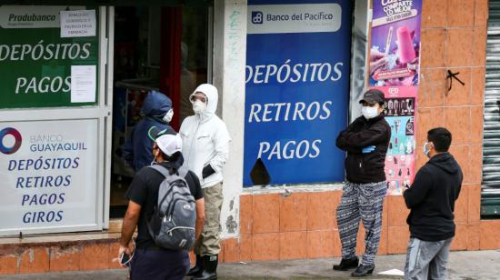 Personas hacen fila en los exteriores de un corresponsal no bancario en Quito, en 2020. 