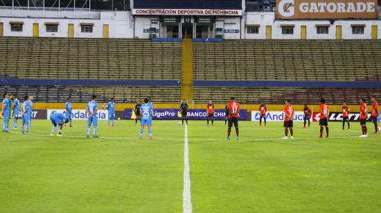 Jugadores de Católica y Aucas guardan un minuto de silencio en el partido del domingo 16 de agosto de 2020, en Quito.