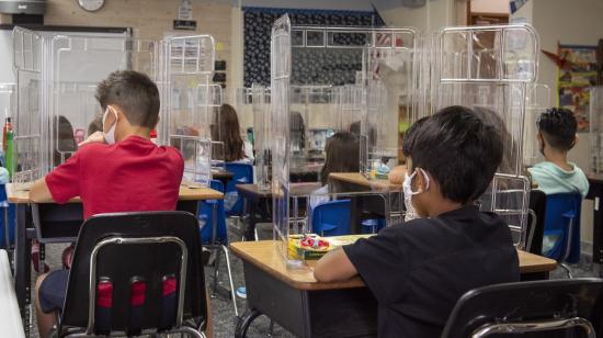 Niños de una escuela en Estados Unidos en pupitres con divisores de acrílicos, el 24 de agosto de 2020.