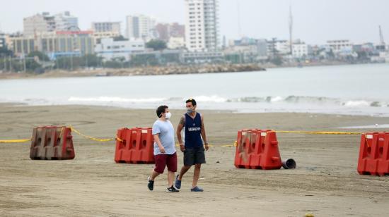 Dos personas con mascarillas caminan por una playa en Santa Elena, el 24 de agosto de 2020.