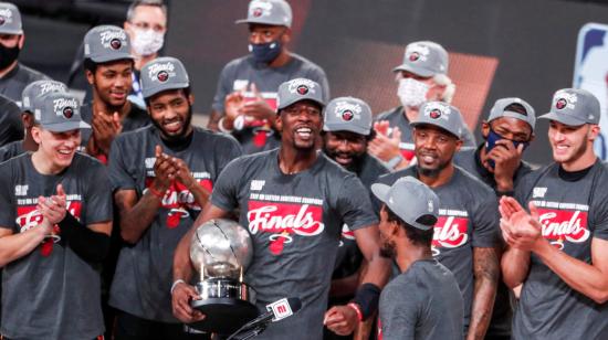 El alero del Miami Heat, Bam Adebayo, sostiene el trofeo del Campeonato de la Conferencia Este mientras celebra con sus compañeros de equipo después del sexto juego de playoffs de la final de la Conferencia Este de la NBA.