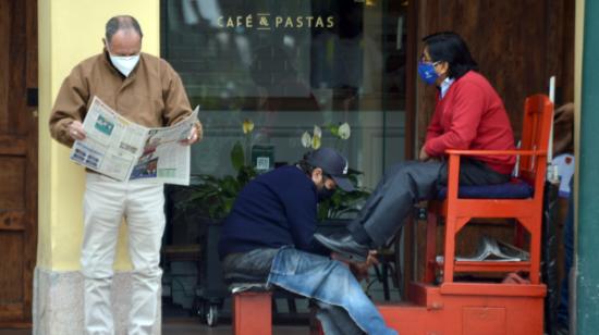 Una persona lustra los zapatos de un hombre en Cuenca, el 6 de octubre de 2020.