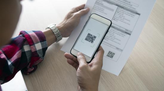 A man uses a smartphone to scan the QR code to pay monthly credit card bills after receiving an invoice sent to home. Online bill payment concept