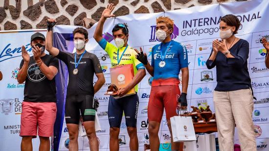 Jorge Montenegro (centro) levanta su brazo y festeja el título del Tour de Galápagos, el domingo 13 de diciembre de 2020.