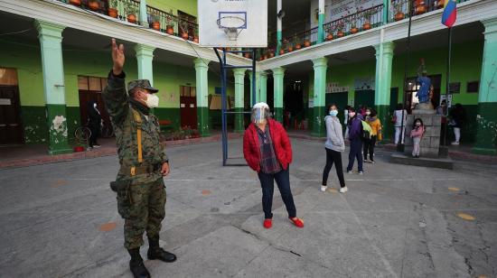 Un militar da directrices a una ciudadana en un recinto electoral de Quito, el 7 de febrero de 2021. 