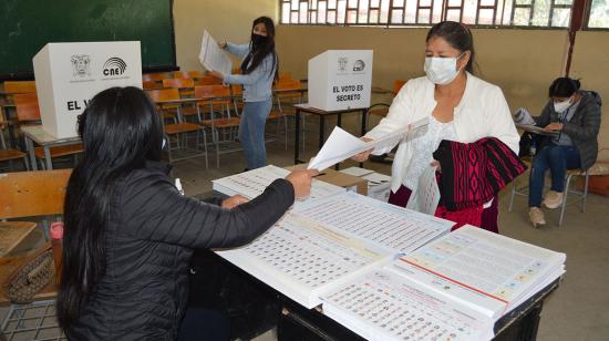 Una ciudadana recibe las papeletas electorales en un recinto de Cuenca, durante las elecciones presidenciales y legislativas del 7 de febrero de 2021.