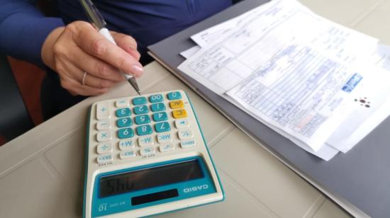 Imagen referencial. Una mujer haciendo cálculos con unas facturas, en Ecuador, en 2021.