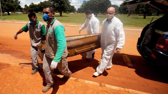 Trabajadores cargan un féretro con una víctima mortal de covid-19 rumbo a su entierro en el cementerio Campo da Esperança, en Brasilia.