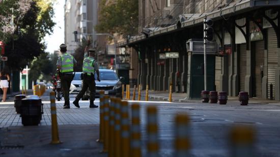 Un policía detiene a uno de los vehículos que transitan por una avenida vacía en Chile, el 27 de marzo de 2021.