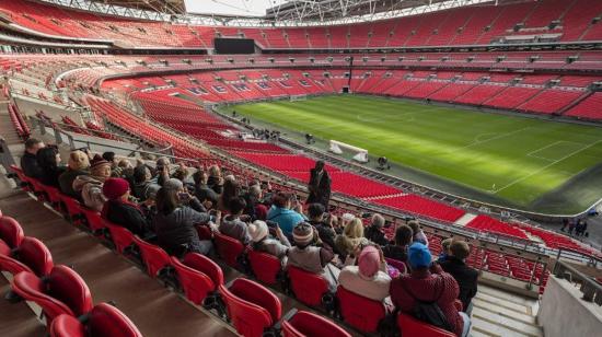 Aficionados en escuchando al guía del tour del estadio de Wembley.