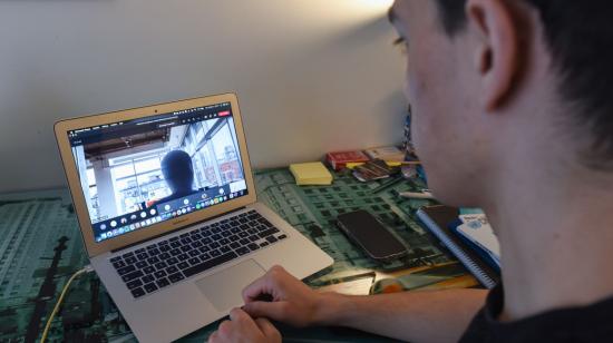 Imagen referencial. Joven frente a una computadora reflejado en la pantalla por la cámara web.