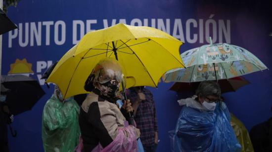 Adultos mayores hacen fila bajo la lluvia, en espera de vacunarse en los exteriores del Centro de Exposiciones Quito, 23 de abril de 2021. 