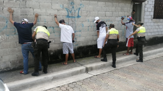 Personal de la Policía Nacional registrando a tres ciudadanos en la Florida, Guayaquil, durante el toque de queda.