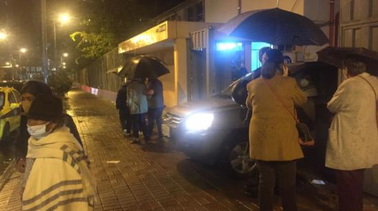 Ciudadanos esperan bajo la lluvia su entrada el colegio Sebastián de Benalcázar, en Quito, la noche del 26 de abril de 2021.