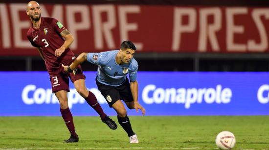 Mikel Villanueva de Venezuela disputa un balón con Luis Suárez de Uruguay, en un partido de las Eliminatorias al Mundial de Catar 2022, el martes 8 de junio de 2021, en el estadio Olímpico de Caracas.