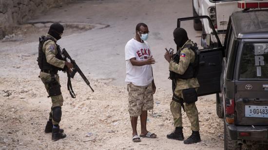 Policías haitianos revisan el celular de un hombre que tomaba fotografías en una calle cercana a la residencia donde fue asesinado el expresidente Jovenel Moise, el 15 de julio de 2021.