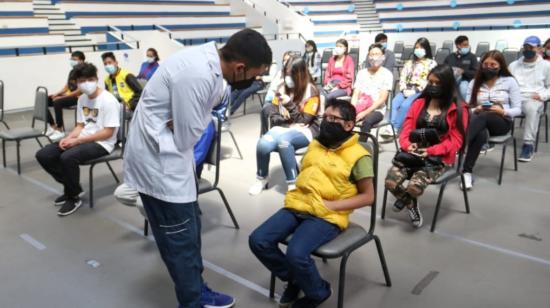 En médico conversa con un adolescente antes de aplicarle la vacuna contra el Covid-19, el 28 de julio de 2021, en Quito.