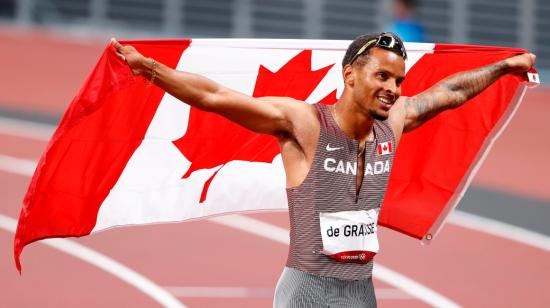 El canadiense Andre De Grasse celebra con la bandera de su país tras ganar la medalla de oro en la final de 200 metros masculino, en los Juegos Olímpicos de Tokio.