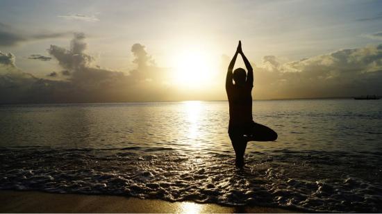 Imagen referencial de una mujer haciendo yoga en una playa.