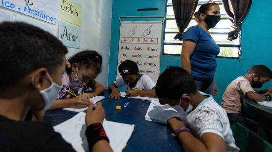 Niños hacen tareas en sus cuadernos durante una clase en la casa, el 20 de agosto de 2021, en Petare, Caracas (Venezuela).