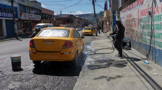 Dos personas lavan un taxi en la calle Cusubamba, en Quito, el 3 de septiembre de 2021.