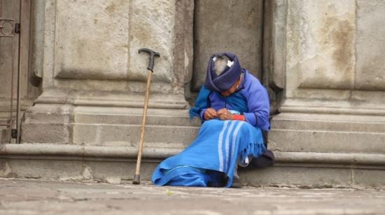 Una mujer de la tercera edad sentada en las afueras de una iglesia en el Centro Histórico de Quito, el 25 de agosto de 2021.