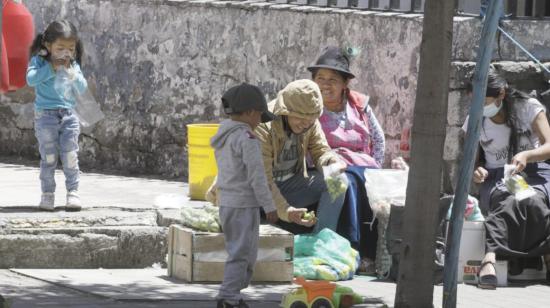 Dos niños acompañan a sus padres en la venta de productos en Quito, el 28 de octubre de 2021.