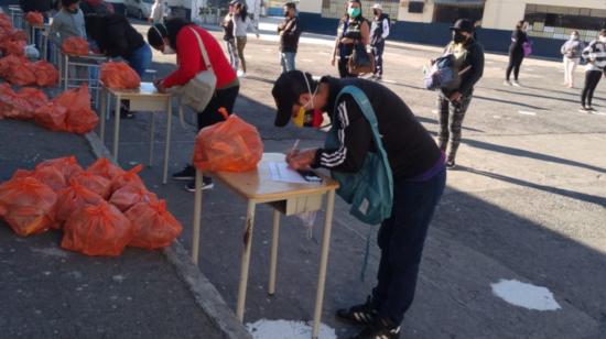 Padres de familiar reciben el desayuno escolar par sus hijos, en Quito, el 6 de octubre de 2021.