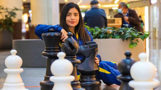 Anahí Ortiz posa junto a las piezas del tablero gigante de ajedrez, en un centro comercial de Quito, el 10 de noviembre de 2021. 