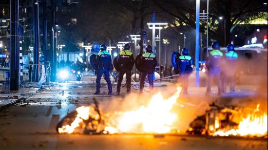 Policías junto a los restos de llantas y motos quemadas tras las protestas en Róterdam (Países Bajos) en contra de las medidas anti-Covid, el 20 de noviembre de 2021. 