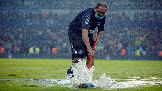 Un empleado de Emelec barriendo el agua en el estadio Capwell, con una pequeña escoba, en la final de la LigaPro, el 12 de diciembre de 2021. 